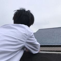 a person sitting on a ledge looking at the sky