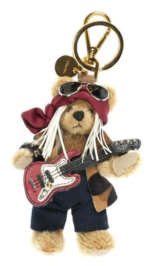 a teddy bear holding a guitar keychain in its mouth and wearing sunglasses, bandannas and a pirate hat