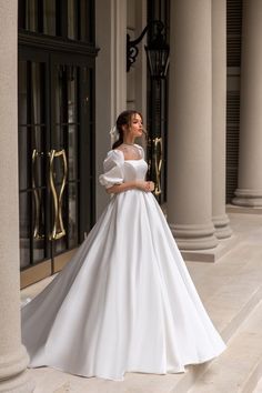 a woman in a white wedding dress standing on some steps