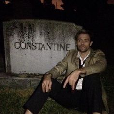 a man sitting on top of a cement bench in front of a stone sign that says constante