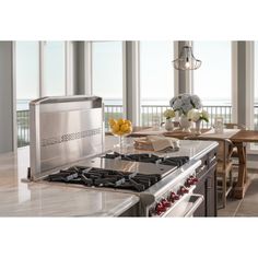 a stove top oven sitting inside of a kitchen next to a table with flowers on it