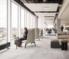 a woman sitting on a chair in an office looking out the window at her laptop