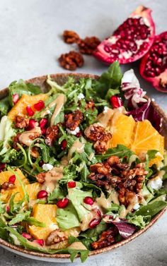 a salad with oranges, walnuts and dressing in a bowl on a table