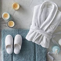 a robe and slippers sitting on top of a blue towel next to candle holders