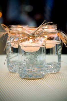 three mason jars filled with candles on top of a table