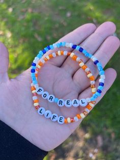 a hand holding two bracelets with words that spell out the word love in white letters