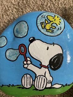 a painted rock with a cartoon dog holding a magnifying glass in it's mouth