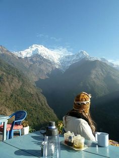 a person sitting at a table with mountains in the background