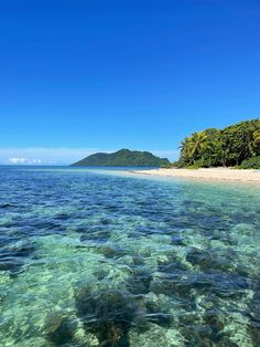 the ocean is crystal clear and blue with some trees in the background on an island