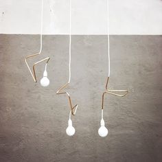 three light bulbs suspended from the ceiling in an empty room with concrete flooring and white walls