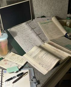 many papers and pens are on the desk next to a cup with a straw in it