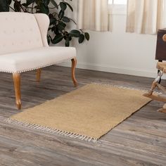 a living room with wooden floors and a white chair next to a rug on the floor