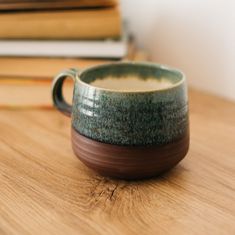 a coffee cup sitting on top of a wooden table next to books and pencils