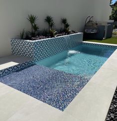 a small pool in the middle of a yard with plants and rocks on either side