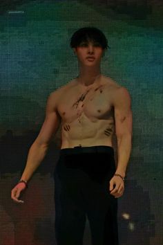 a shirtless man standing in front of a screen