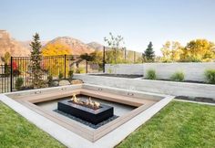 an outdoor fire pit with grass and mountains in the backgroung area behind it