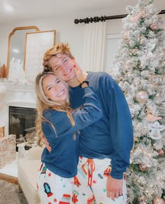 a man and woman standing in front of a christmas tree