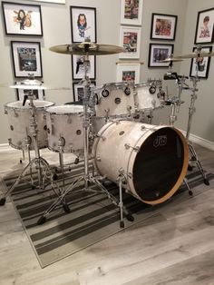 a drum set sitting on top of a hard wood floor next to framed pictures in a room