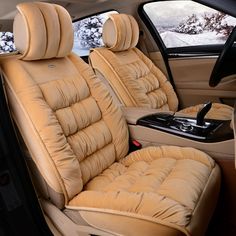 the interior of a car with beige leather seats and black dash board, in front of snow - covered trees