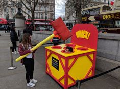 a woman standing next to a giant red and yellow box