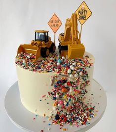 a birthday cake decorated with construction vehicles and sprinkles