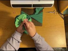 someone is doing something on top of a desk with scissors and green cloth tied to it