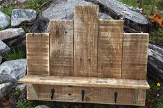 a bench made out of wooden planks sitting in front of some rocks and flowers