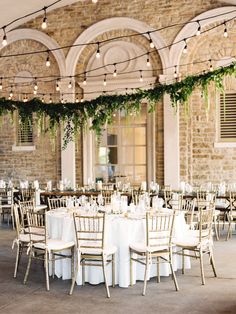 an indoor venue with tables and chairs set up for a formal dinner or function, surrounded by greenery