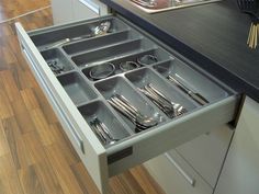 an open drawer in a kitchen with utensils and silverware inside it on the counter