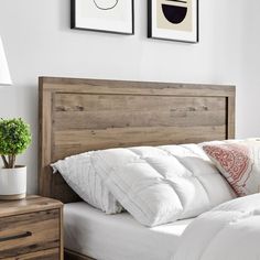 a bed with white sheets and pillows next to two pictures on the wall above it