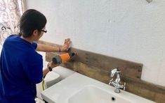 a boy in blue shirt using a hammer to fix a sink with wooden planks