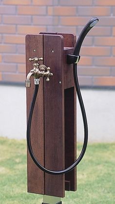 an old fashioned water faucet is attached to a wooden stand in the grass