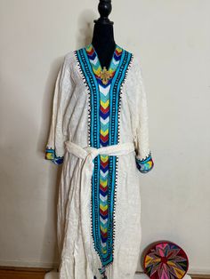 Ethiopian and Eritrean traditional dress, habesh kemis, beautiful,simple,featuring intricate embroidery with vibrant colors. The design suggests it might be from a specific cultural or ethnic background. The dress has a prominent V-shaped neckline with multicolored geometric            100%cotton Traditional Handloom Festival Dress, Traditional Kurta With Geometric Embroidery For Eid, Multicolor Kaftan With Resham Embroidery, Multicolor Resham Embroidered Kaftan With Traditional Drape, Multicolor Resham Embroidery Kaftan With Traditional Drape, Traditional Dresses With Multicolor Embroidery And Woven Motifs, Traditional Geometric Embroidery Kurta For Festivals, Cotton Traditional Wear With Geometric Embroidery For Festivals, Folk Style Embroidered Dress For Festive Season