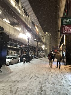 two people walking down a snowy street at night