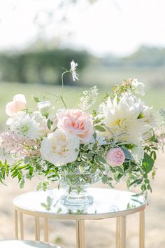 a vase filled with white and pink flowers on top of a table next to a mirror