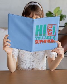 a woman holding up a book with the words hi you are a superhero