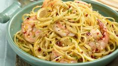 a blue bowl filled with pasta and shrimp