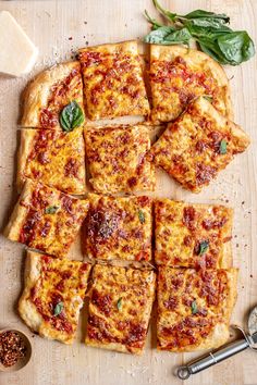 sliced pizza sitting on top of a wooden cutting board next to cheese and basil leaves