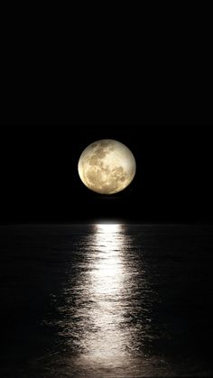 the full moon shines brightly in the dark night sky over the water's surface