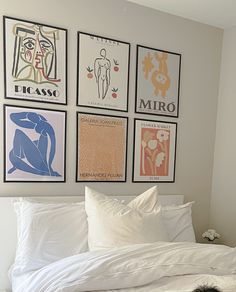 a bed with white sheets and four posters on the wall