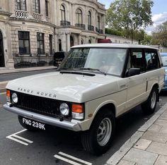 an old car is parked on the side of the road in front of a building