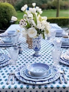 a blue and white table setting with flowers in a vase