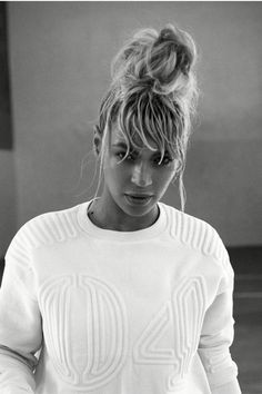 a black and white photo of a woman in a sweater looking at her cell phone