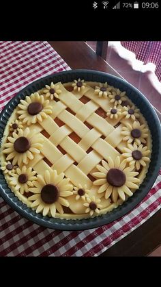 a pie with sunflowers on it sitting on top of a checkered table cloth