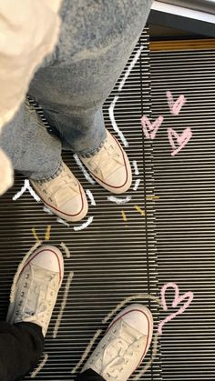 two people standing on an escalator next to each other with hearts drawn on them