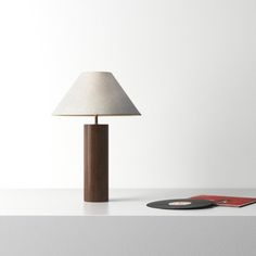 a table lamp sitting on top of a white counter next to a record player and remote control