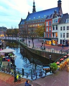 people are walking down the street next to some buildings and water in front of them