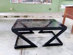 a glass coffee table sitting on top of a cement floor next to a wooden chair