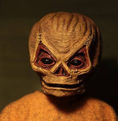 an alien head is shown in front of a black background with red eyes and brown hair