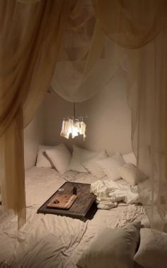 an unmade bed with white sheets and drapes on the headboard is shown